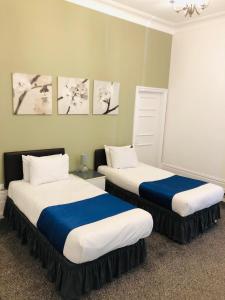 a room with two beds with blue and white sheets at Albany, Brighton & Hove in Brighton & Hove