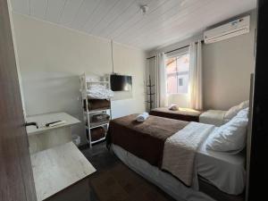 a small bedroom with two beds and a television at Pousada Carolina Apartamentos in Penha