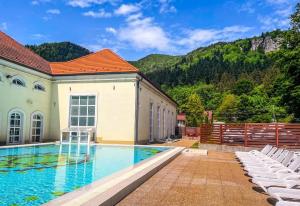 a swimming pool with white chairs next to a building at Pensiunea Vanatorul in Băile Tuşnad