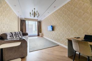 a living room with a couch and a desk with a laptop at Большая трехкомнатная, с видом на горы in Zhezdi