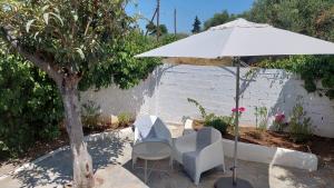 a table and chairs under an umbrella next to a tree at Modern Summer House Kalimera in Epanomi
