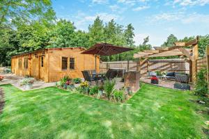 a backyard with a wooden cabin with a lawn at Woodlands Lavender Lake House in Long Bennington