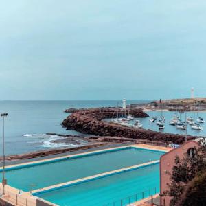 a swimming pool next to the ocean with boats in the water at Keiraleagh House in Wollongong +90 photos
