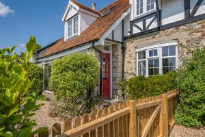 a cottage with a red door and a wooden fence at Woodstock in Ventnor