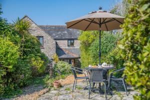 a table and chairs under an umbrella in a garden at Alice Cottage - Corfe Castle in Corfe Castle