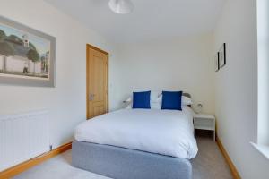 a white bedroom with a bed with blue pillows at Flat 4 Penlu in Swanage