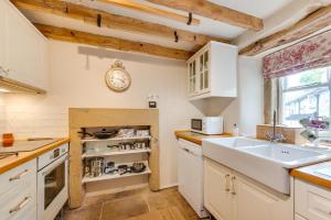 Una cocina con un fregadero y un reloj en la pared. en Holly Homestead, en Middleton