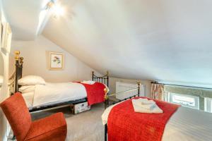 a attic bedroom with two beds and a chair at Rose Cottage in Youlgreave
