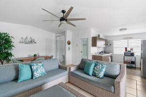 een woonkamer met twee banken en een plafondventilator bij La Casita Blanca - Sun in Fajardo