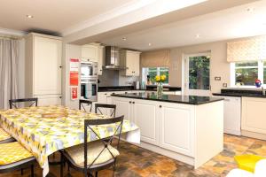 a kitchen with white cabinets and a table and chairs at Artists Coastal Retreat in Wool