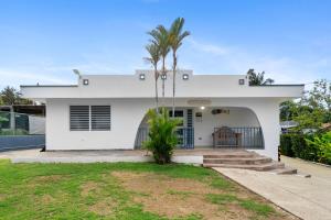 een wit huis met een palmboom ervoor bij La Casita Blanca - Sun in Fajardo