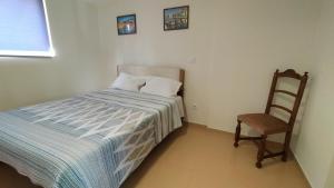 una piccola camera da letto con un letto e una sedia di Casa T2- Entre Porto e Aveiro a Carregosa