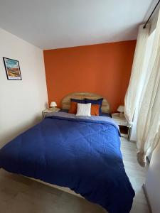 a bedroom with a blue bed with an orange wall at Au Cœur d Orgelet in Orgelet