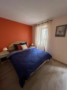 a bedroom with a large blue bed with orange walls at Au Cœur d Orgelet in Orgelet