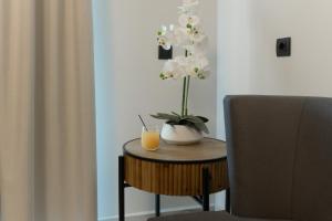 a table with a vase of flowers and a glass of orange juice at Envy Seaside Suites,By IdealStay Experience in Heraklion