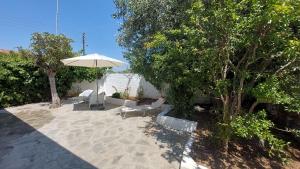 a patio with an umbrella and chairs and trees at Modern Summer House Kalimera in Epanomi +20 photos