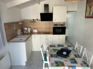 a kitchen with a table with chairs and a sink at Maison du Marais Vendéen in Saint-Benoist-sur-Mer