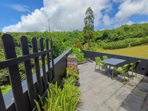 un patio con mesa y sillas junto a una valla en Canada da Ribeira, en Ponta Garça