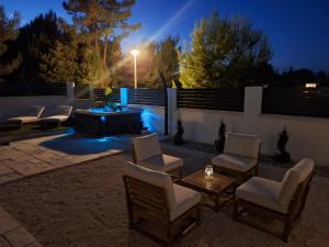 a patio with chairs and a fire pit at night at Villa Amphora in Vir