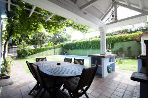un patio con mesa y sillas bajo una pérgola blanca en La Casa Azul con piscina, en Miengo