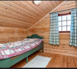 ein Schlafzimmer mit einem Bett in einer Blockhütte in der Unterkunft Karíbu-Welcome in Øyuvstad