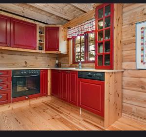 eine rote Küche mit Holzwänden und Holzböden in der Unterkunft Karíbu-Welcome in Øyuvstad