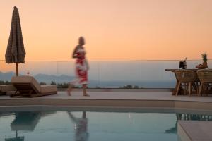a woman walking next to a swimming pool at Ocean Luxury Villas in Volimes