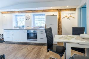 a kitchen with white cabinets and a table and chairs at Ferienwohnung Tilda in Redewisch