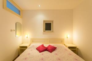 ein Schlafzimmer mit einem Bett mit zwei roten Kissen in der Unterkunft Apartments Margaretic in Dubrovnik
