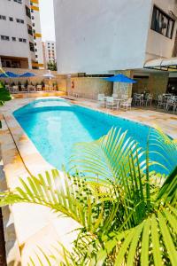 a swimming pool with tables and chairs in a building at El Aram Beach Boa Viagem in Recife