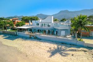 a blue house on the beach with mountains in the background at VELINN Pousada Solar Grego in Ubatuba +34 photos