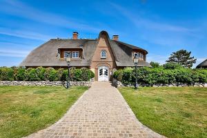 a house with a thatched roof and a brick driveway at Hygge Suite Sylt Kampen in Niederdorla