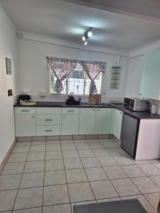 a kitchen with white cabinets and a black counter top at Ulu Garden Cottage in Ramsgate