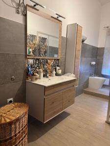 Un baño con lavabo, espejo y bañera. en DA BARBARINA Casa Vacanze sud Sardegna, en Capoterra