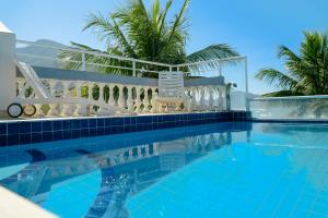 a swimming pool with chairs and palm trees in the background at VELINN Pousada Solar Grego in Ubatuba