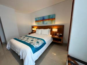 a hotel room with a large bed and two lamps at Hotel Atrium Plaza in Barranquilla