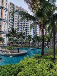 a resort pool with palm trees and buildings at Timurbay Seafront By Moonlight in Kuantan