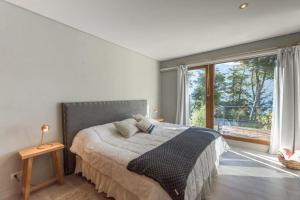 a bedroom with a bed and a large window at Paraiso correntoso Hermoso departamento con vista al lago y piscina climatizada in Villa La Angostura +46 photos