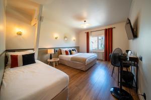 ein Hotelzimmer mit zwei Betten und einem Fernseher in der Unterkunft Hôtel Rive Sud in Chinon