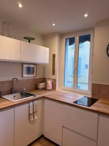 Una cocina con gabinetes blancos y un fregadero y una ventana. en Il Piccolo - Cosy emplacement de rêve, en Bandol 32 fotos más