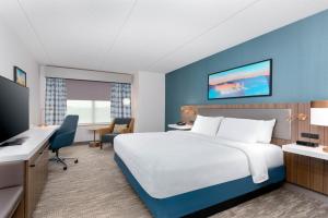 a hotel room with a bed and a desk at Hilton Garden Inn Buffalo Airport in Cheektowaga