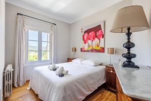 sypialnia z białym łóżkiem z lampką i oknem w obiekcie Villa du Val - Welkeys w Aix-en-Provence