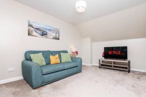 Una sala de estar con un sofá azul y un televisor en The Steading, Kingsbarns., en Kingsbarns