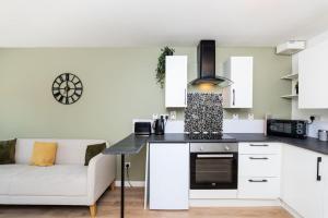 Una cocina con gabinetes blancos y un sofá blanco. en The Steading, Kingsbarns., en Kingsbarns