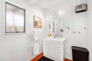 a white bathroom with a sink and a mirror at HORIZON SURF LODGE plus private spa in Raglan +30 photos