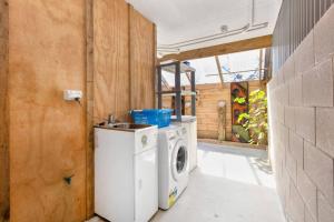 a washer and dryer in a room with a wall at HORIZON SURF LODGE plus private spa in Raglan