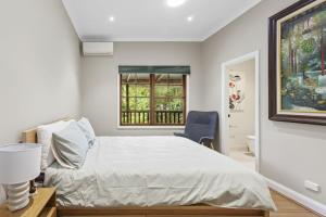 a bedroom with a bed and a chair and a window at Carmelia Garden View Haven for Families and Friends in Wentworth Falls