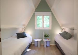 デュルビュイにあるBirdie Forest Lodge - voor golf & MTB, met bergingのベッド2台と窓が備わる屋根裏部屋です。