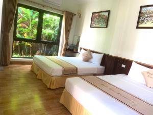 two beds in a room with a window at Tam Coc Minh Gia Homestay in Ninh Binh