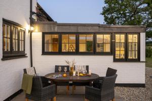 eine Terrasse mit einem Holztisch und Stühlen in der Unterkunft Historic Farmhouse Retreat Foot of the South Downs in Wivelsfield